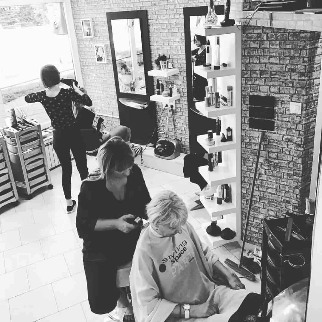 Dvije frizerke rade s klijenticama u salonu, crno-bijela fotografija